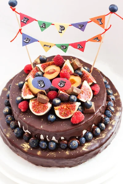 Chocolate cake with icing, decorated with fresh fruit — Stock Photo, Image