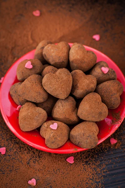 Trufas de chocolate em forma de coração na placa vermelha — Fotografia de Stock