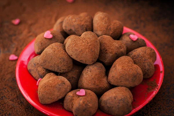 Trufas de chocolate em forma de coração na placa vermelha — Fotografia de Stock