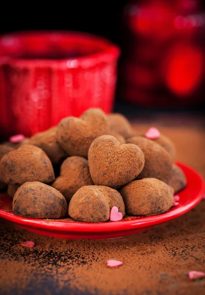 Trufas de chocolate em forma de coração na placa vermelha — Fotografia de Stock