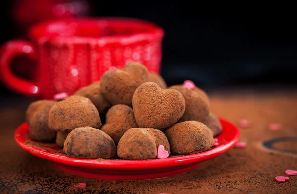 Trufas de chocolate em forma de coração na placa vermelha — Fotografia de Stock