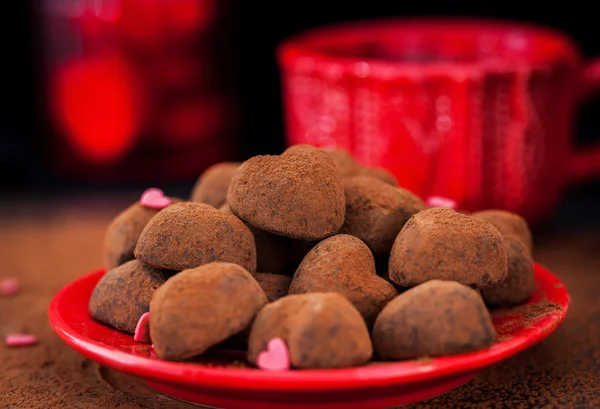 Trufas de chocolate em forma de coração na placa vermelha — Fotografia de Stock