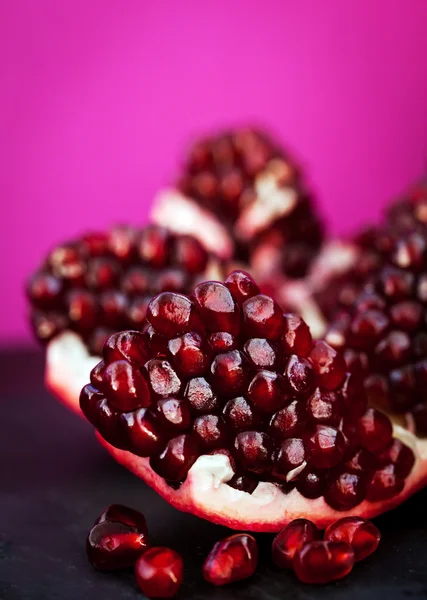 Fresh pomegranate and seeds on black — Stock Photo, Image