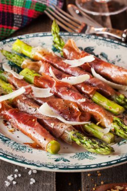 Parma ham plaka üzerinde yeşil kuşkonmaz sarılı