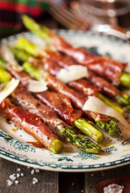 Parma ham plaka üzerinde yeşil kuşkonmaz sarılı