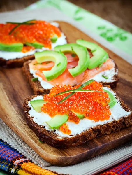 Appetizer with red caviar, avocado, salmon and creamcheese — Stock Photo, Image