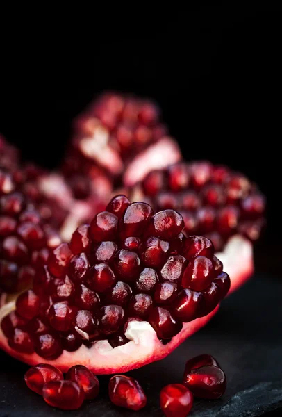 Fresh pomegranate and seeds on black — Stock Photo, Image