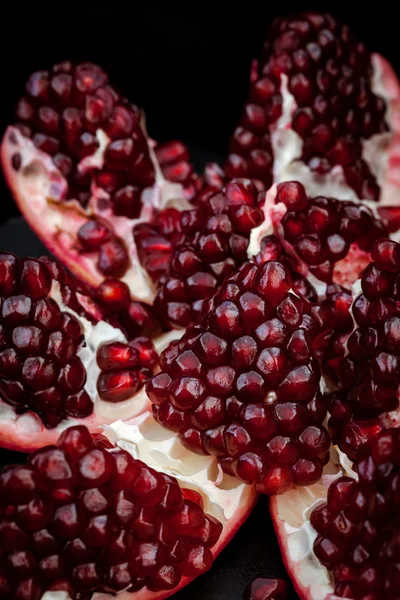 Fresh pomegranate and seeds on black — Stock Photo, Image