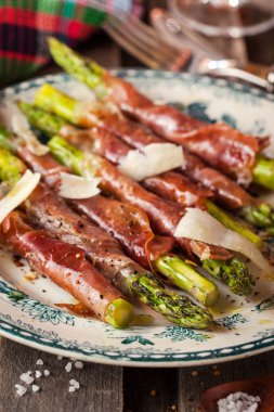 Parma ham plaka üzerinde yeşil kuşkonmaz sarılı