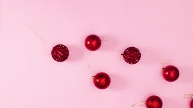 Kırmızı Noel süslemesi topları, pastel pembe temalı altın yıldızlarla ortaya çıkar. Hareketi durdur