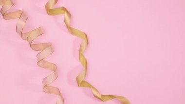 Noel altın süsleri, toplar, yıldızlar ve kurdeleler pastel pembe temanın sol tarafında görünür. Hareketi durdur