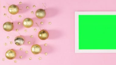Yeşil ekranlı beyaz çerçeve ve pastel pembe temalı altın Noel süslemesi. Hareketi durdur