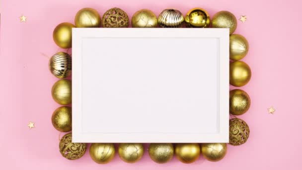 Gold Weihnachtsschmuck und Sterne erscheinen unter weißem Rahmen für Text auf pastellrosa Thema .Stop-Motion