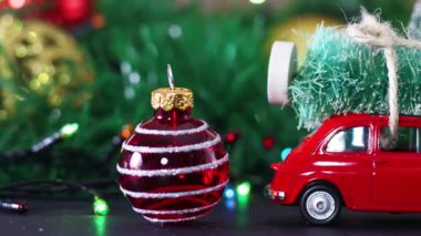 Çatıda Noel ağacı, Noel süsleri ve yanıp sönen ışıklar olan küçük kırmızı bir araba.