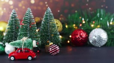 Noel süslemeleri yanıp sönen ışıklar, Noel ağaçları ve çatısında ağaç olan kırmızı bir araba.