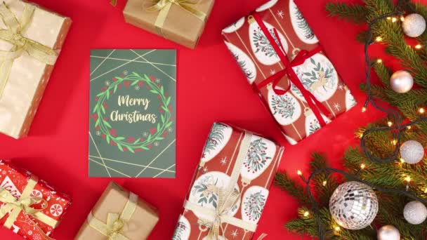Weihnachtsgrußkarte Und Geschenke Mit Kieferngirlanden Mit Blinkenden Lichtern Auf Rotem — Stockvideo