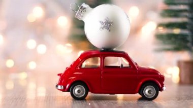 Çatıda beyaz Noel süsü olan küçük kırmızı bir araba.