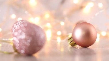 Noel ağacı için pastel pembe Noel süsü yanıp sönen ışıklarla birlikte masada.