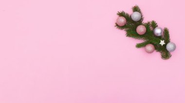 Çam dalları, gümüş, pembe süslemeler ve kar taneleri içeren süslemeler, pastel pembe temanın sağ tarafında görünür. Hareketi durdur