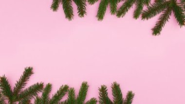 Pembe ve gümüş süslemeli Noel Çam dalları pastel pembe temanın üstünde ve altında görünür. Hareketi durdur