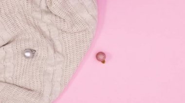 Noel süsleri ve yanıp sönen ışıklarla örülmüş süveter pastel pembe temada görünür. Hareketi durdur