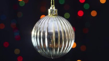 Arkasında yanıp sönen ışıklar olan altın gibi parlak bir Noel süsü.