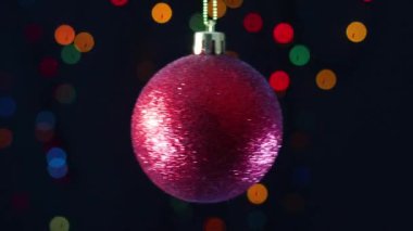 Kırmızı parıltılı Noel süsü yanıp sönen ışıklarla sallanıyor.