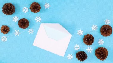 Noel dilekleri için zarfın içinde kozalaklı ve kar taneli mavi temalı kağıtlar. Hareketi durdur