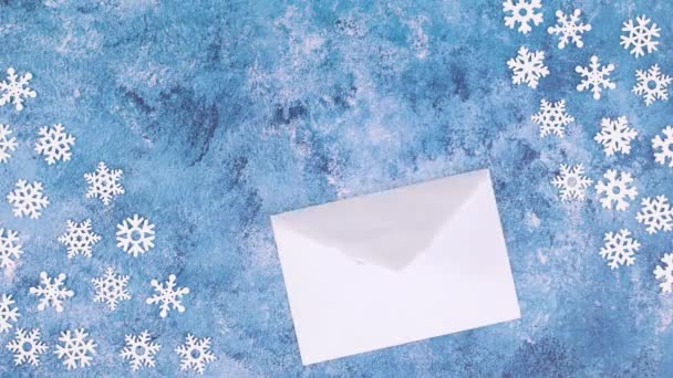 Papier Für Text Erscheint Aus Einem Umschlag Mit Blauen Schneeflocken — Stockvideo
