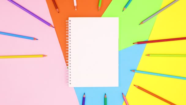 彩色铅笔在笔记本周围出现并消失在圆圈中 停止运动 — 图库视频影像