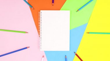 Açık defter ve renkli kalemler etrafta beliriyor. Hareketi durdur 