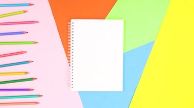 Renkli kalemlerin yanında metin için açık bir defter var. Hareketi durdur