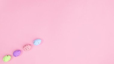 Farklı renklerde Paskalya yumurtaları pastel pembe temada tek bir çizgi halinde görünür. Hareketi durdur
