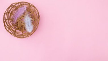Ahşap sepet pastel pembe temada görünür ve içinde Paskalya yumurtası ve tüy bulunur. Hareketi durdur