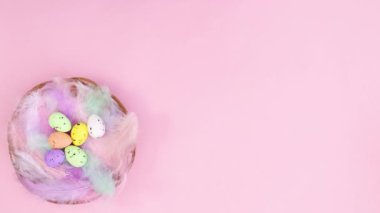 Paskalya yumurtalı ahşap sepet pastel pembe temanın sol tarafında görünür. Hareketi durdur