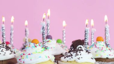 Doğum günü partisi için tatlı keklerin üzerine mum üflüyorum.