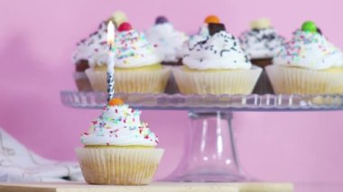 Doğum günü partisinde masada servis edilen kekin üzerinde yanan doğum günü mumu. Kapat.