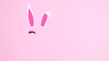 Yaratıcı Paskalya tavşanı pastel pembe temalı kirpiklerle ortaya çıkar ve göz kırpar. Düz konum stop hareketi 