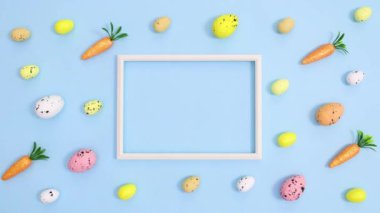 Yumurta ve havuçlu Paskalya deseni ve ortadaki uzay çerçevesini parlak pastel mavi arka planda kopyalamak. Dur hareketi düz yatıyordu