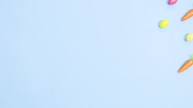 Yumurta ve havuç pastel mavi arka planda yaratıcı bir Paskalya şablonu oluşturur. Dur hareketi düz yatıyordu