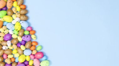 Canlı renkli yumurtalar pastel mavi arka planda hareket eder. Hareketi durdur