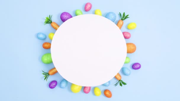 具有创意的复活节彩蛋和胡萝卜出现在浅蓝色背景的纸卡下 停止运动最小平铺 — 图库视频影像
