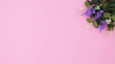 Lavanta ve okaliptüs yapraklı çiçek buketi pastel pembe arka planda görünür. Hareketi durdur