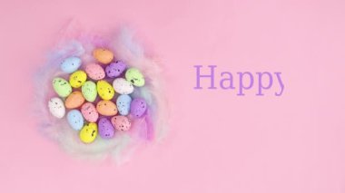 Mutlu Paskalyalar, pastel pembe arka planda canlı yumurtalarla yuvanın yanına yaz. Dur hareketi düz yatıyordu