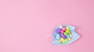 Paskalya yumurtalı yüz maskesi pastel pembe arka planda görünür. Dur hareketi düz yatıyordu