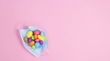 Paskalya yumurtalarının pastel pembe arka planda döndüğü yüz maskesi. Hareketi durdur
