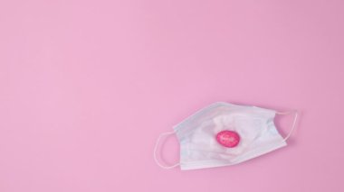 Paskalya yumurtaları pastel pembe arka planda yüz maskesinde görünür. Minimum düz yatış Dur hareketi