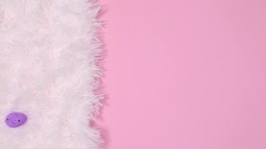 Paskalya yumurtaları beyaz kürkte ve kağıt kart kağıtları da pastel pembe arka planda görünür. Hareketi durdur