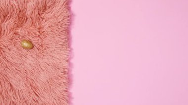 Altın yumurtalar pastel pembe arka planda kürkte görünür. Dur hareketi düz yatıyordu 