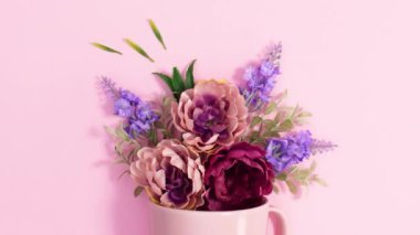 Pastel pembe arka planda fincanda güzel bir bahar çiçeği aranjmanı. Hareketi durdur